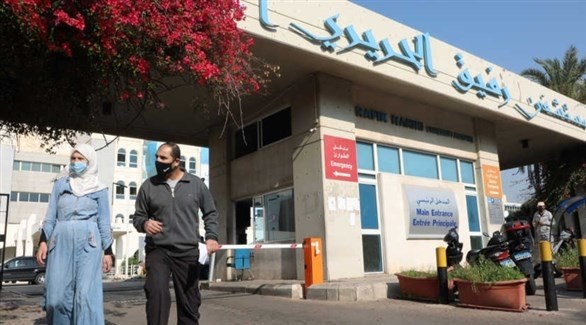 لبنانيان أمام مستشفى رفيق الحريري في بيروت (رويترز)
