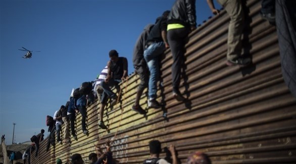 مهاجرون مكسيكيون يحاولون عبور الجدار الفاصل على الحدود (أرشيف)