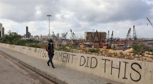 لبناني يمر أمام أنقاض ميناء بيروت امام شعار "حكومتي فعلت هذا" (أرشيف)