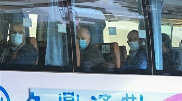 محققو الصحة العالمية في حافلة بووهان الصينية اليوم (أ ف ب)  