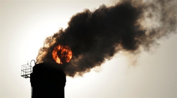 الشمس كما بدت خلف السحاب الخارج من مداخن المصانع (أرشيف / رويترز)