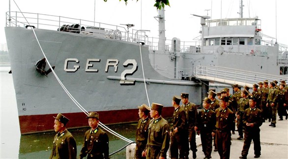 عسكريون كوريون شماليون أمام السفينة الأمريكية المحتجزة في بيونغ يانغ (أرشيف)