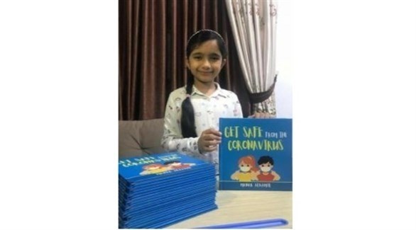 الطفلة العراقية منار مع كتابها حول فيروس كورونا
