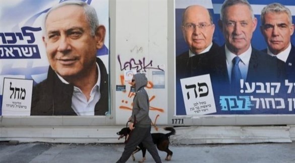 إسرائيلي يمر برفقة كلبه من أمام ملص انتخابي (أرشيف)
