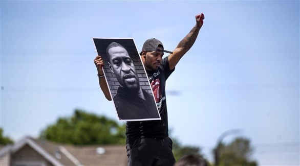 متظاهر أمريكي يرفع صورة جورج فلويد (أرشيف)