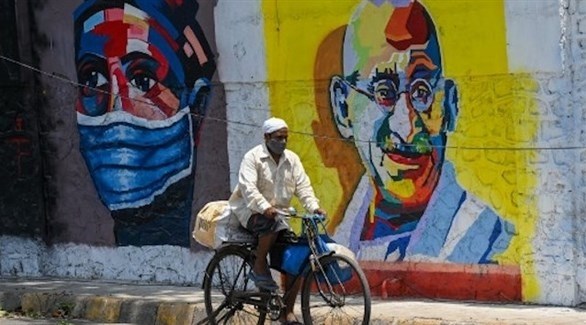 هندي يقود دراجته بموازاة جدارية لمهاتما غاندي (أرشيف)