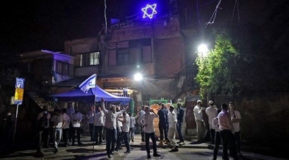 مستوطنون إسرائيليون أمام إحدى منازل حي الشيخ جراح المهدد بالمصادرة من قبل إسرائيل (تويتر)