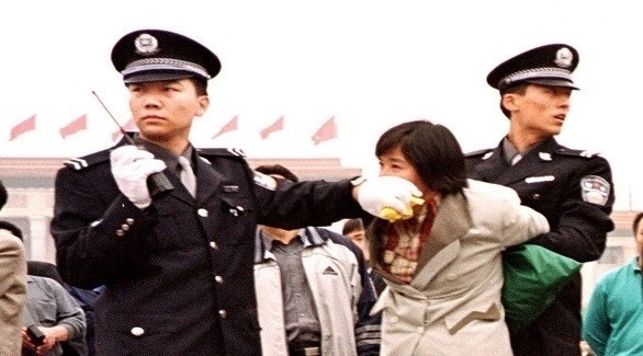 شرطيان صينيان أثناء اعتقال أحد أتباع طائفة فالون غونغ (أرشيف)