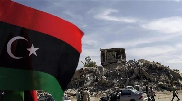 العلم الليبي ظاهراً أمام مبنى مهدم في ليبيا (أرشيف / أ ف ب)