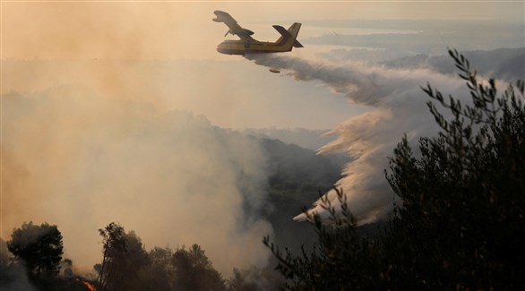 طائرة مكافحة النيران ترمي حمولتها من الماء فوق منطقة بتراس اليونانية (رويترز) 