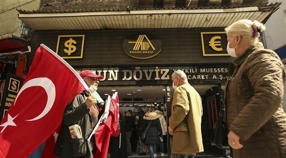 شخص يرفع مجموعة من الأعلام التركية بالقرب من أحد محلات الصيرفة (أرشيف / أ ب )
