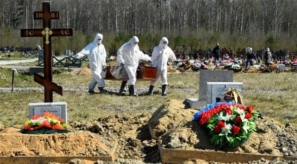 عمال مقبرة روسية ينقلون تابوت أحد ضحايا كورونا (أرشيف)