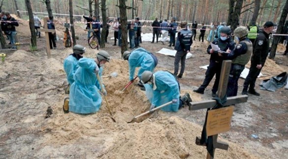 محققون في مقبرة جماعية في أوكرانيا (أ ف ب)