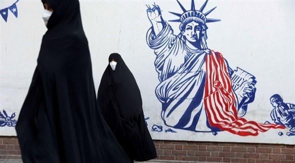سيدات إيرانيات وخلفهم صورة ممزقة لتمثال الحرية (أرشيف)