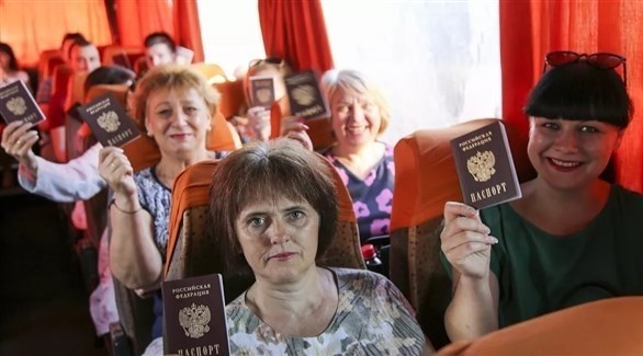 أوكرانيات يرفعن جوازات سفرهن الروسية (تويتر)