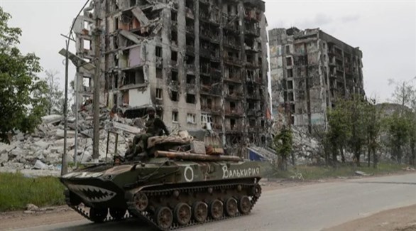 آلية عسكرية تمر بجانب الأبنية المدمرة في أوكرانيا (أرشيف)