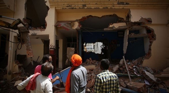 أشخاص ينظرون إلى منزل تم هدمه خلال الاحتجاجات العنفية في الهند (رويترز)