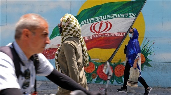 أشخاص يمرون بجانب جدارية تحمل العلم الإيراني (أرشيف)