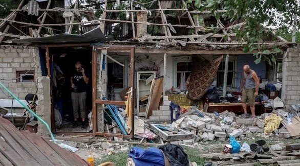 سكان وسط أنقاض منزل في منطقة دونتسك بأوكرانيا (أف ب)
