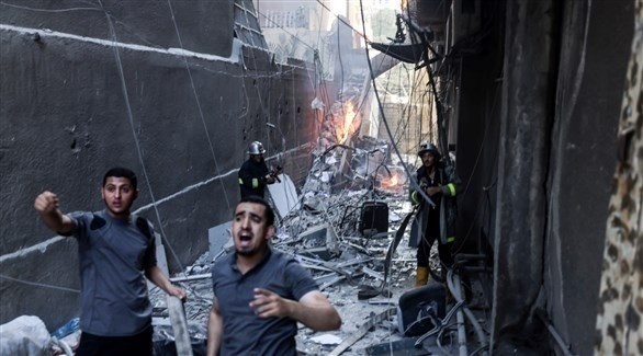 فلسطينيان خلفهم رجلان من الدفاع المدني يحاولون اخماد نيران مشتعلة في منبى تعرض للقصف بغزة (وكالات)
