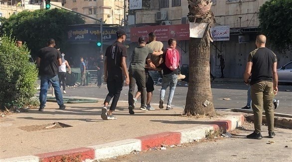 فلسطينيون ينقلون جريحاًُ أصيب في الاشتباكات بنابلس (تويتر)