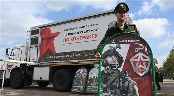 جندي روسي يقف بجوار مركز تجنيد متنقل للخدمة العسكرية (رويترز)