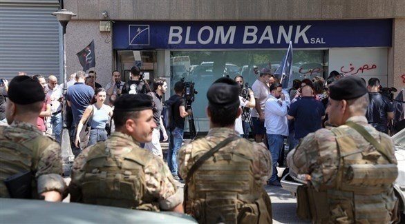 عناصر أمنية تراقب عملية اقتحام سيدة لأحد المصارف في لبنان (رويترز)