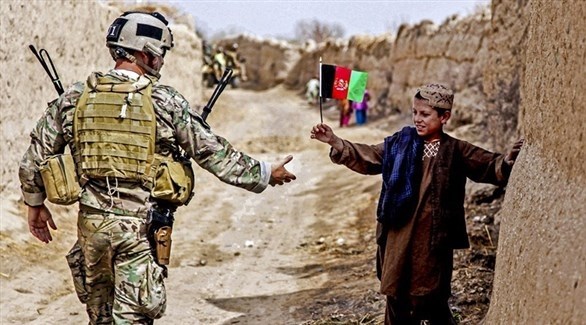 طفل أفغاني يقدم علم بلاده لجندي أمريكي (أرشيف)