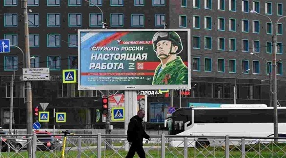 روسي في موسكو أمام لافتة تدعو للالتحاق بالجيش (أرشيف)