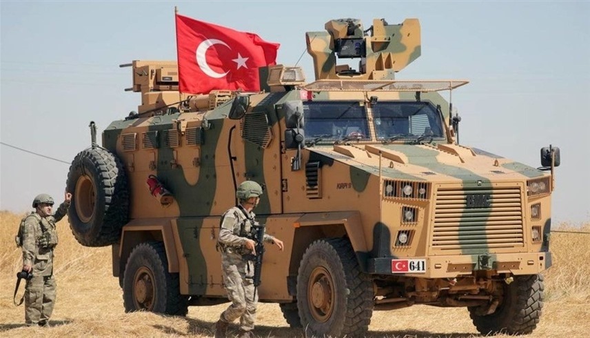 جندي تركي يسير بجوار مركبة عسكرية (رويترز)