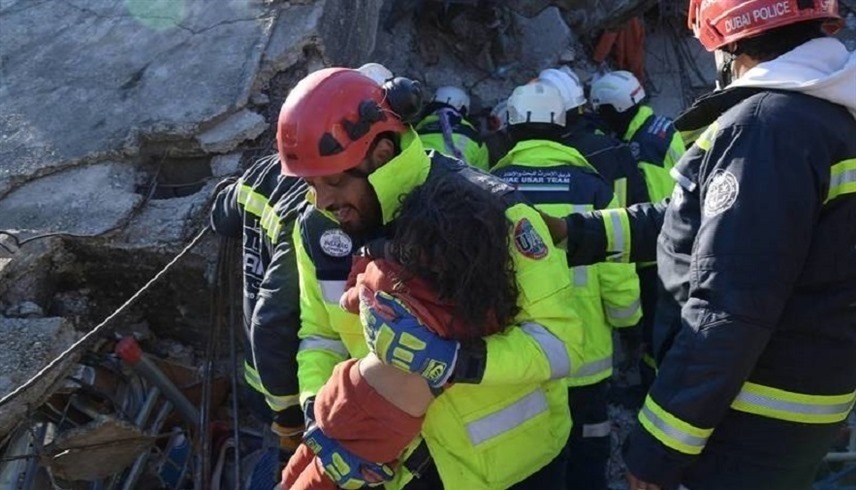 عنصر من فريق الإنقاذ الإماراتي يحتضن طفلة بعد انتشالها من تحت الأنقاض في تركيا (أرشيف)