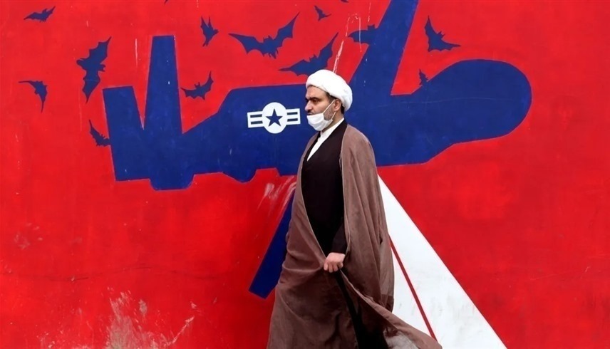 رجل دين إيراني يمر أمام جدارية مناهضة للولايات المتحدة على جدار سفارتها السابقة في طهران (أرشيف)