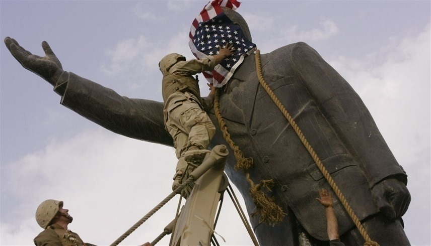 جندي أمريكي يغطي رأس تمثال صدام حسين بساحة الفردوس بعلم بلاده (أرشيف)