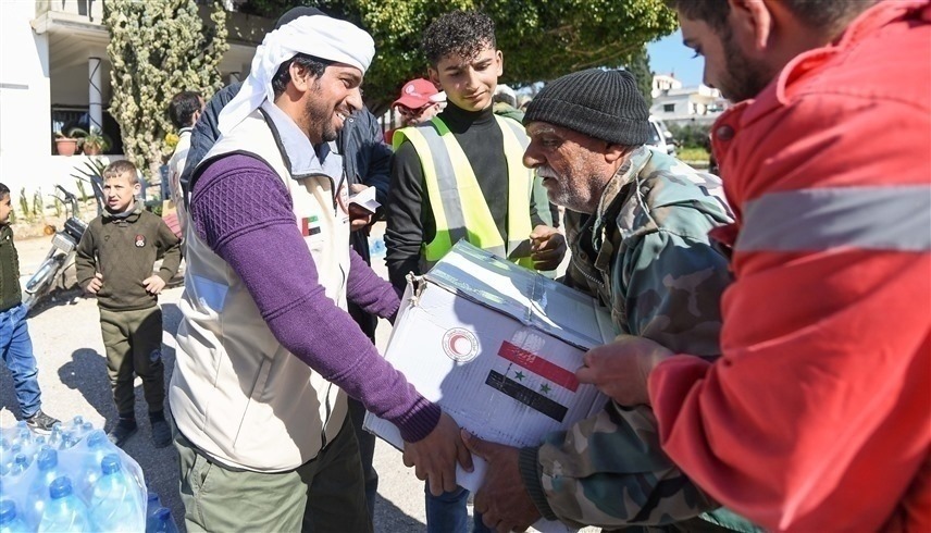 متطوع من الهلال الأحمر الإماراتي يسلم مسناً سورياً مساعدة عينية بعد الزلزال (أرشيف)