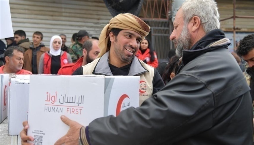 متطوع من الهلال الأحمر مع مستفيد من المساعدات في سوريا (وام)