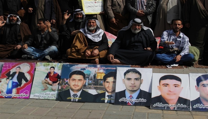 عراقيون يعرضون صوراً لأبنائهم الذين فقدوا بجريمة سبايكر (أرشيف)